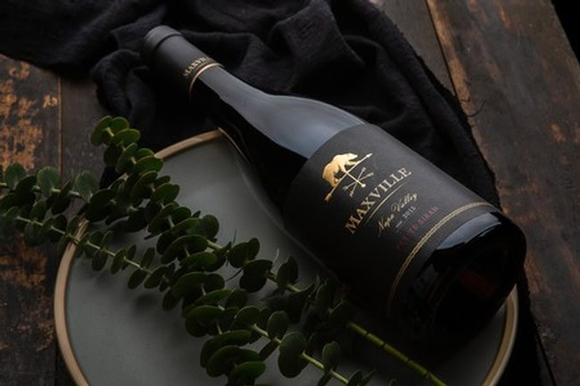 Maxville Winery wine bottle on a plate with greenery, dark wooden background, elegant and sophisticated.