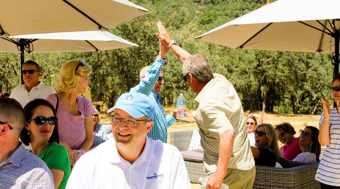 People enjoying outdoor wine tasting at Maxville Winery with scenic greenery in the background.