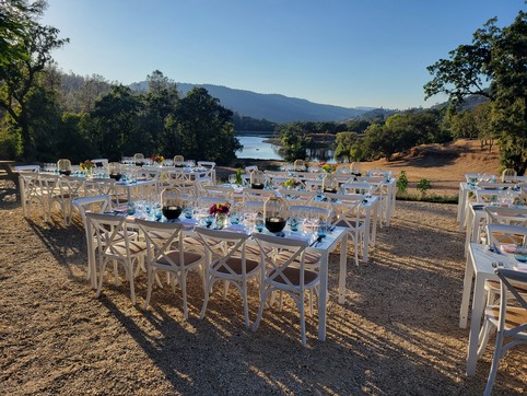 Outdoor dining setup at Maxville Winery with tables, chairs, and scenic river view in the background.
