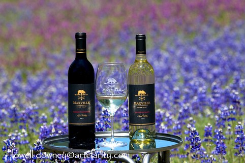 Maxville Winery wine bottles and glass on a table in a lavender field.