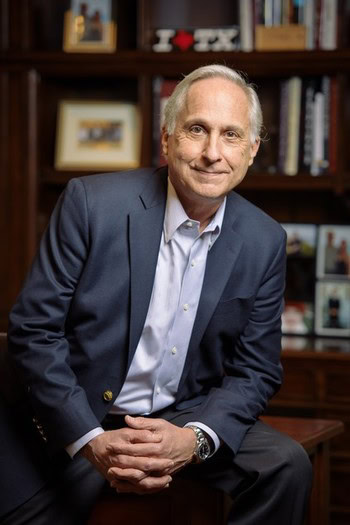 Portrait of a senior man in a suit sitting in a cozy office with bookshelves.