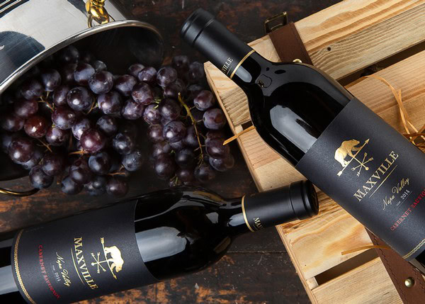 Maxville Winery red wine bottles with grapes and wooden crates for Maxville Forever Wild Membership.