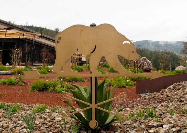 Decorative bear weather vane at Maxville Winery with vineyard and mountains in background.