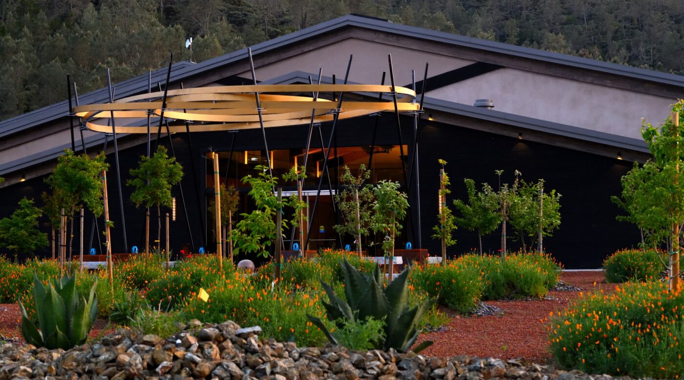 Maxville Winery building with modern architecture surrounded by lush garden and colorful flowers.