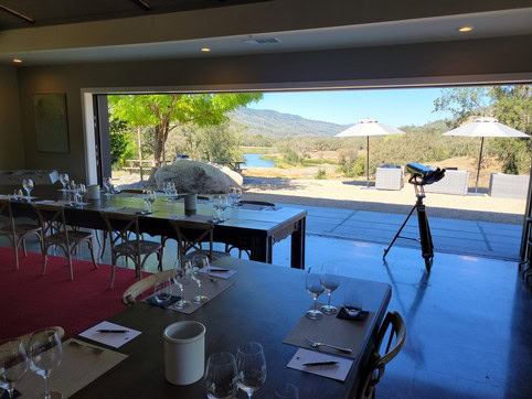 Indoor dining area with large glass window overlooking vineyards and mountains at Maxville Winery.